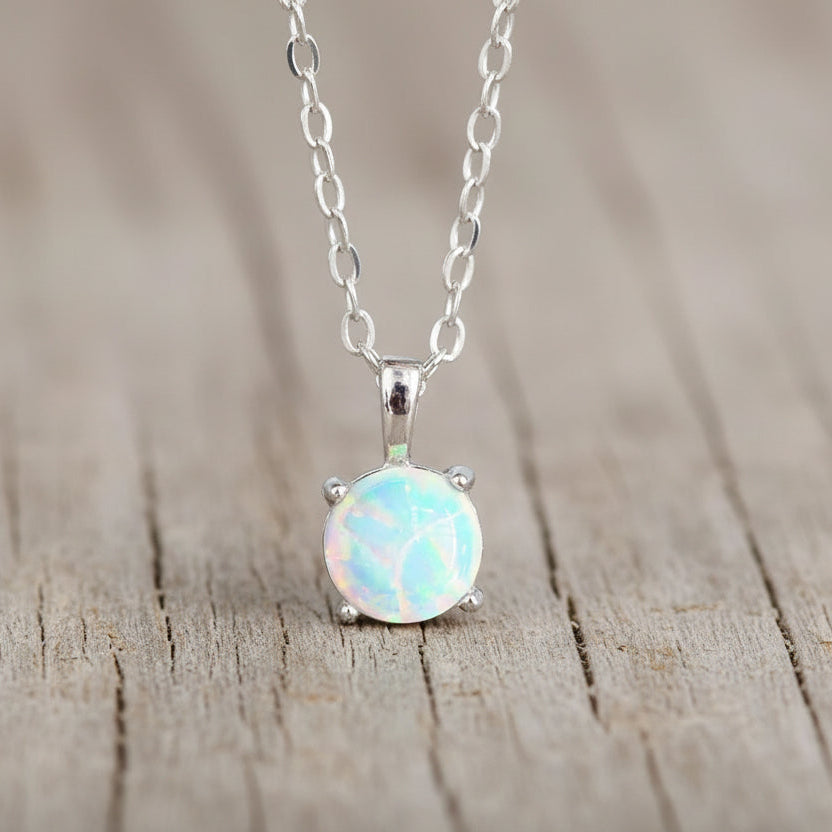 Opal pendant necklace on a chain against a neutral background
