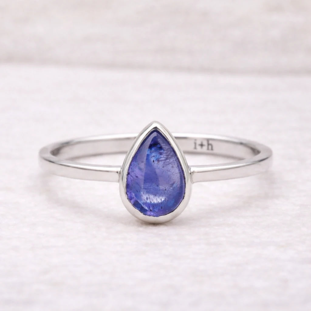 Silver ring with a teardrop-shaped natural tanzanite blue gemstone on a white background