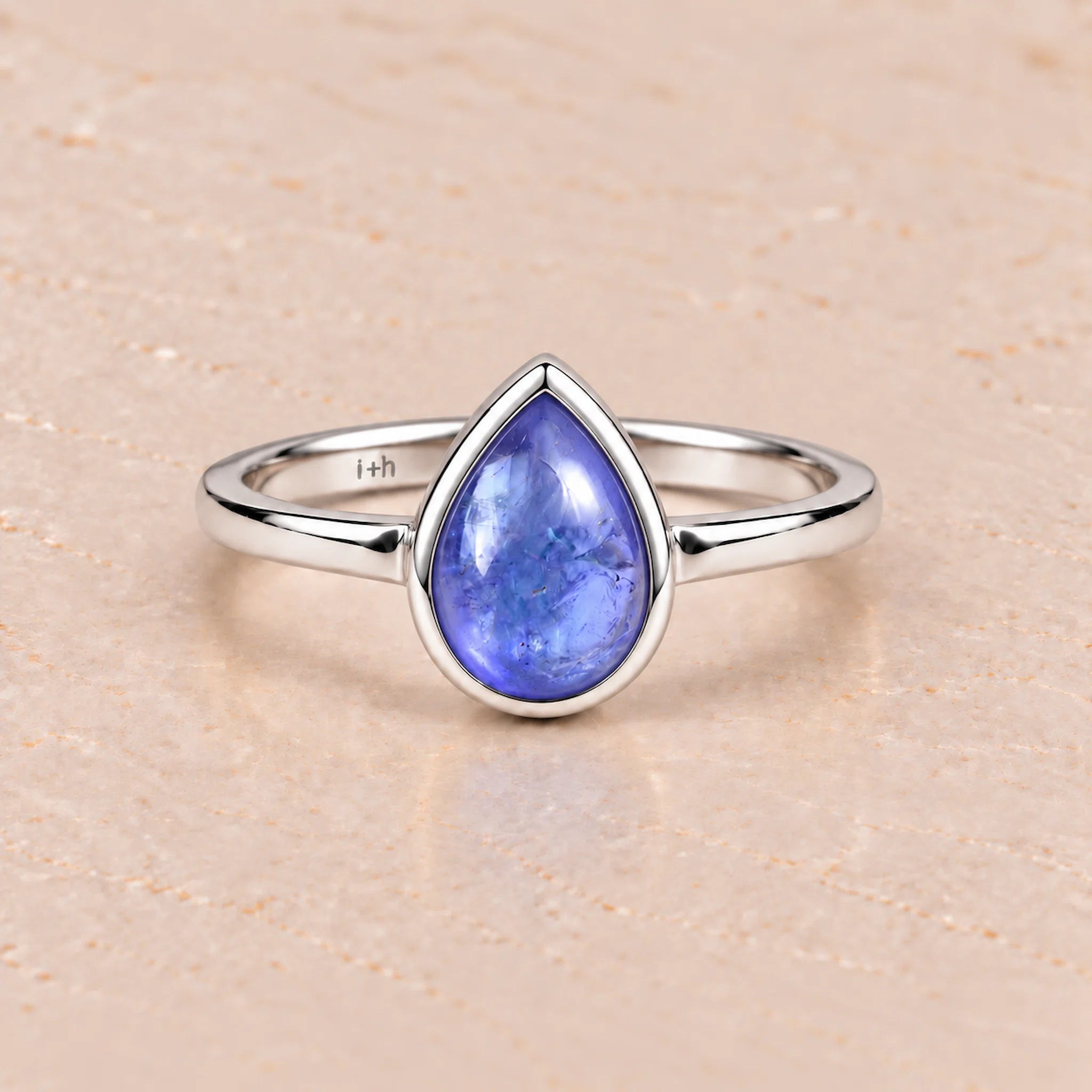 Silver december birthstone ring with a teardrop-shaped natural tanzanite blue gemstone on a white background