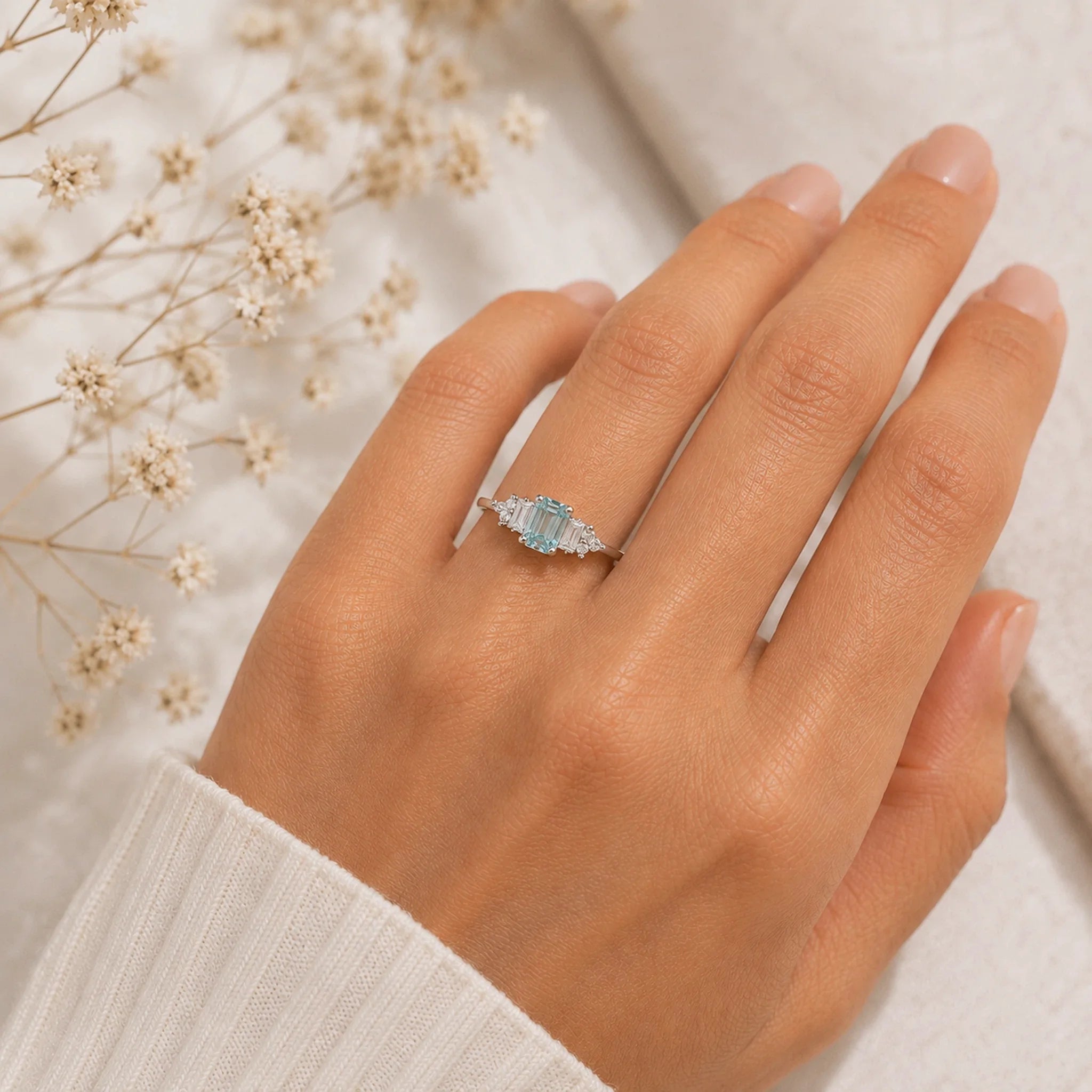 hand wearing a sterling silver deco style ring with emerald-cut cyan moissanite and czs