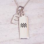 Sterling Silver E Initial and Aquarius Necklace on a fine silver chain against a light wooden background