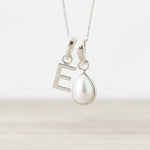 Sterling Silver necklace with 'E' initial pendant and teardrop-shaped mother of pearl charm on a light background