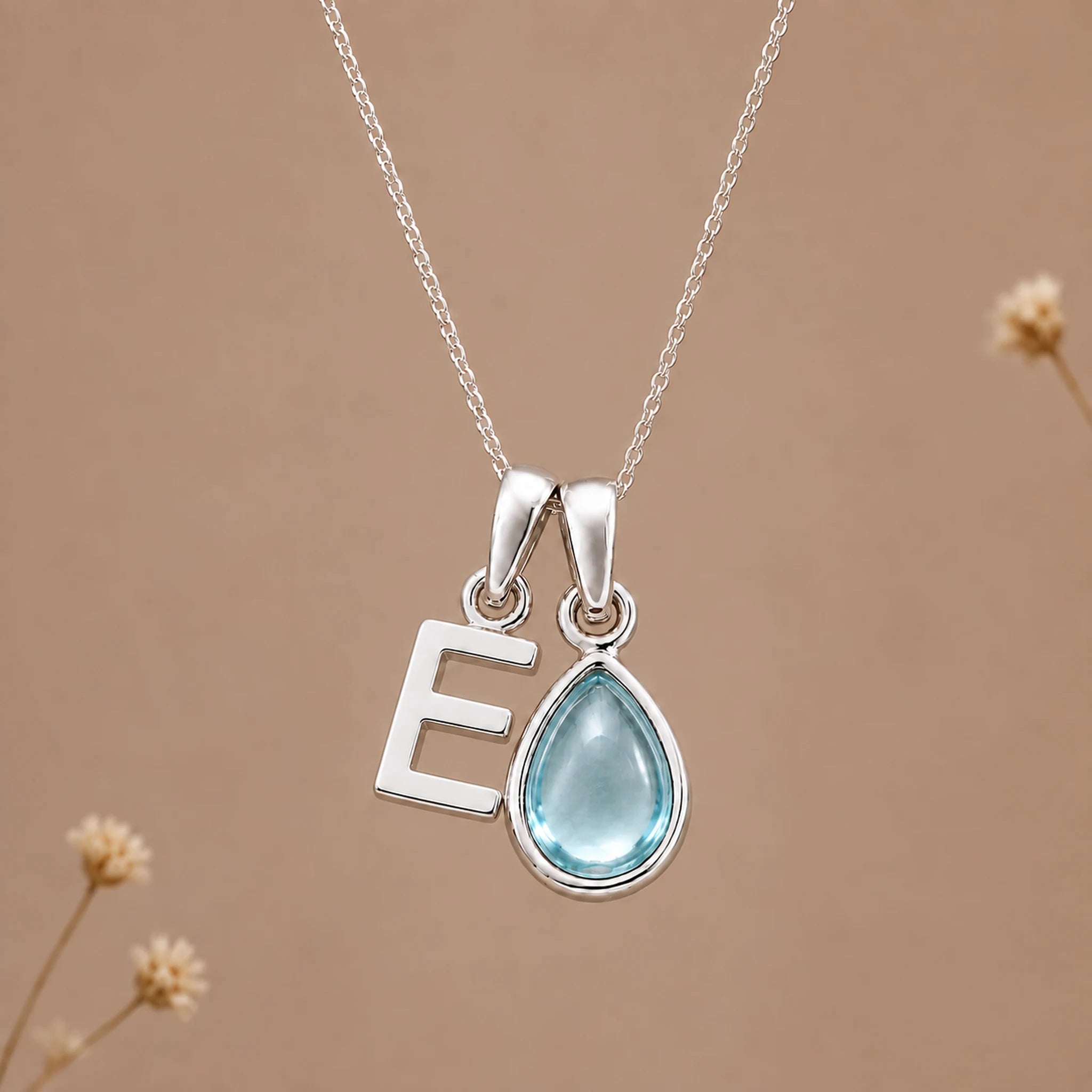 Sterling silver E initial necklace with pale blue March aquamarine in a polished teardrop bezel