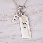Sterling Silver necklace with a 'E' initial pendant and a Taurus zodiac star sign pendant on a light background.