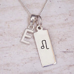 Sterling silver Leo initial necklace with a letter E and engraved zodiac bar on wood