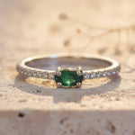 Silver ring with a green gemstone on a textured beige surface