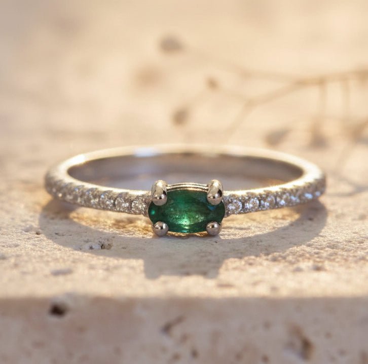 Silver ring with a green gemstone on a textured beige surface
