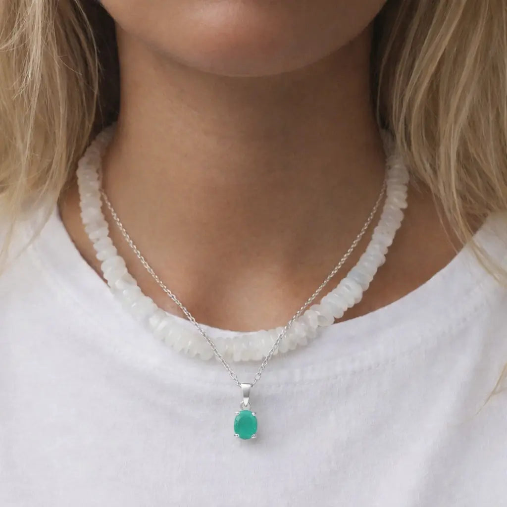 Woman wearing a moonstone beaded necklace and silver emerald necklace 