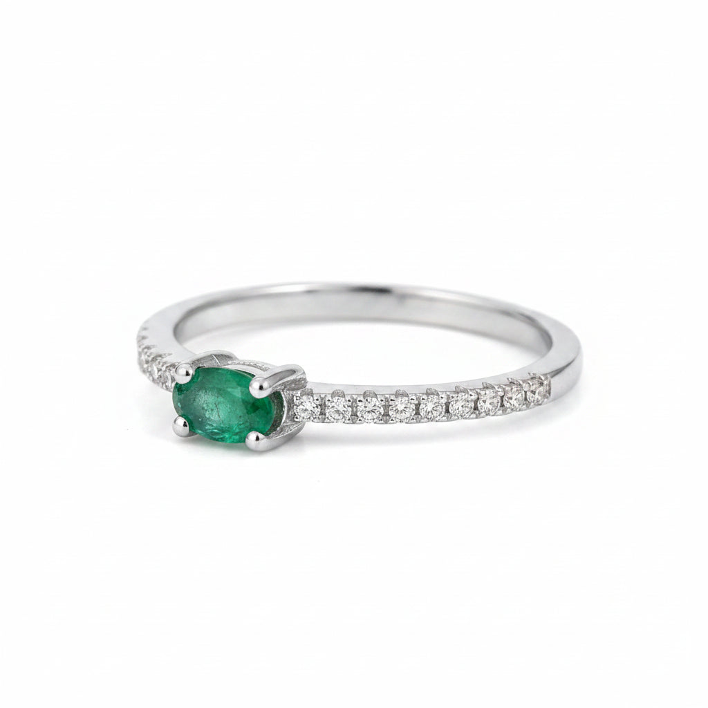 side view of a Sterling Silver Pave Ring with a oval shaped green faceted claw set emerald gemstone on a beige background
