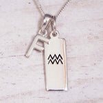 Sterling Silver F Initial and Aquarius Necklace on a fine silver chain against a light wooden background