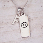 Sterling Silver f Initial Cancer Zodiac Star Sign Necklace on a fine silver chain against a light wooden background
