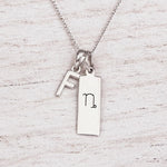 sterling silver initial F pendant and capricorn necklace on a fine silver chain against a light wooden background