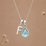 Sterling silver F initial necklace with pale blue March aquamarine in a polished teardrop bezel