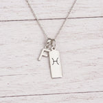 sterling silver F initial Pisces Necklace on a fine silver chain against a light wooden background