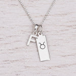 Sterling silver F initial Pendant and Taurus Necklace on a fine silver chain on a light wooden background