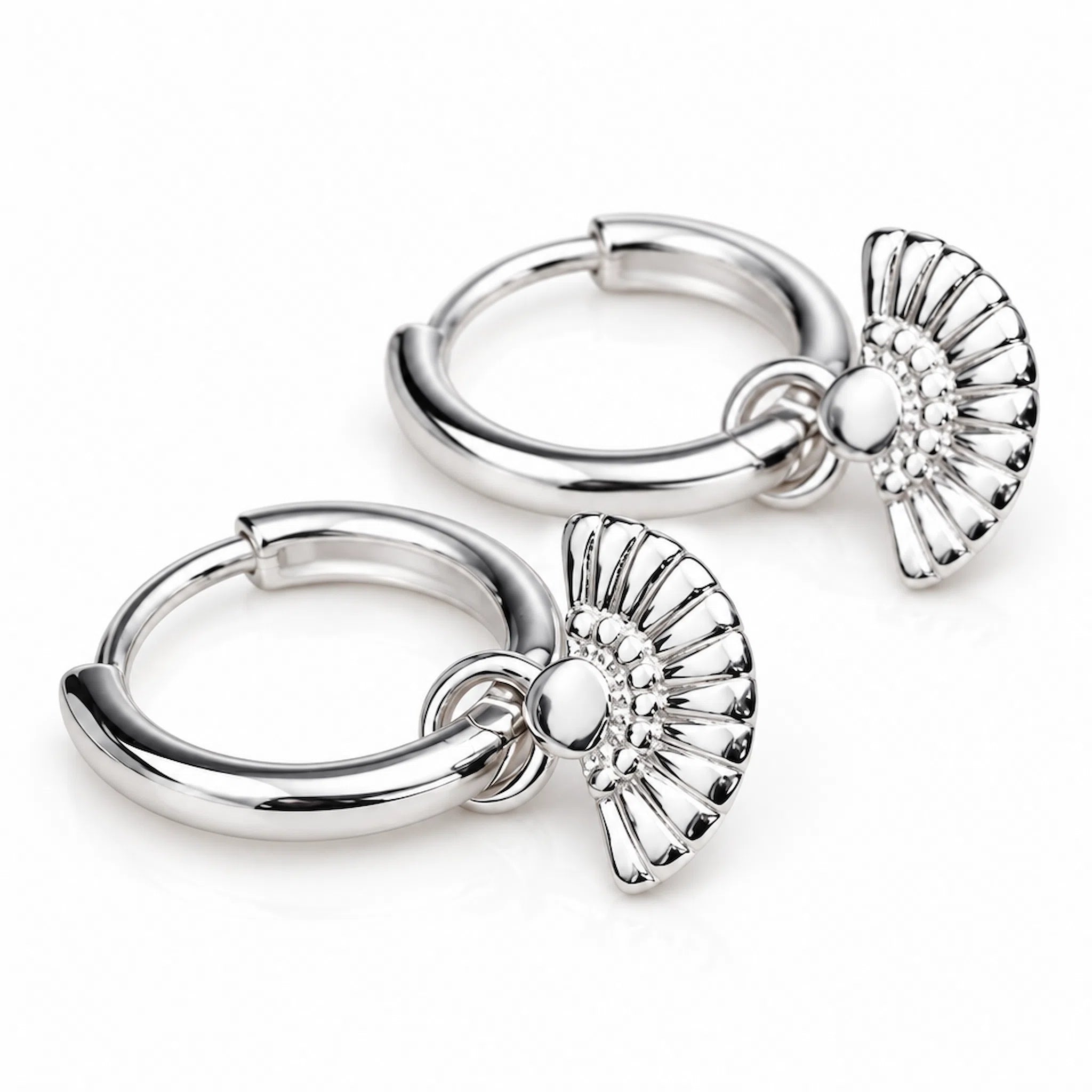 Pair of sterling silver fan hoop earrings on a textured surface.