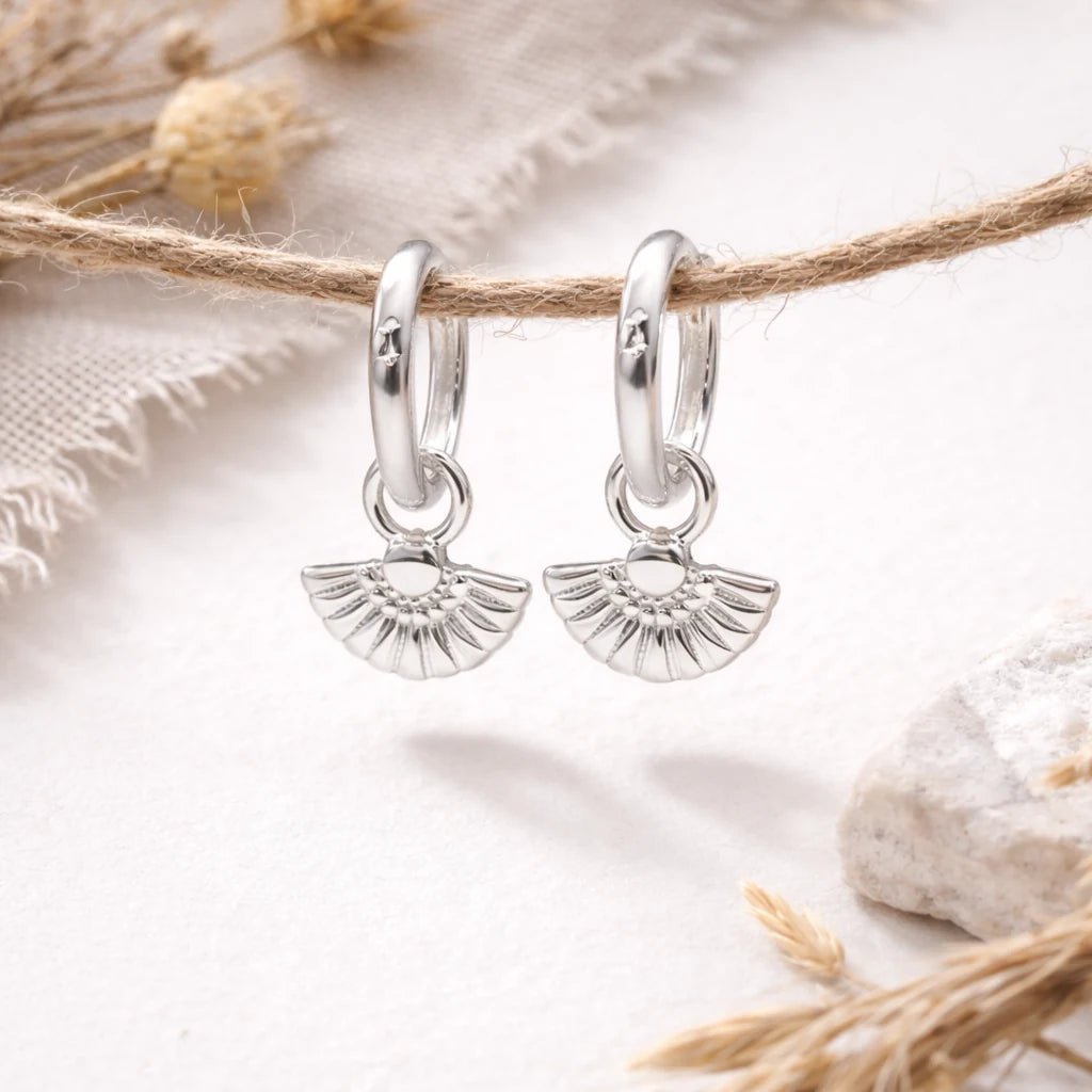 Silver hoop earrings with fan-shaped charms on a natural background