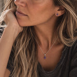 model wearing sterling silver february birthstone jewellery set of dainty natural amethyst pendant necklace and matching stud amethyst earrings
