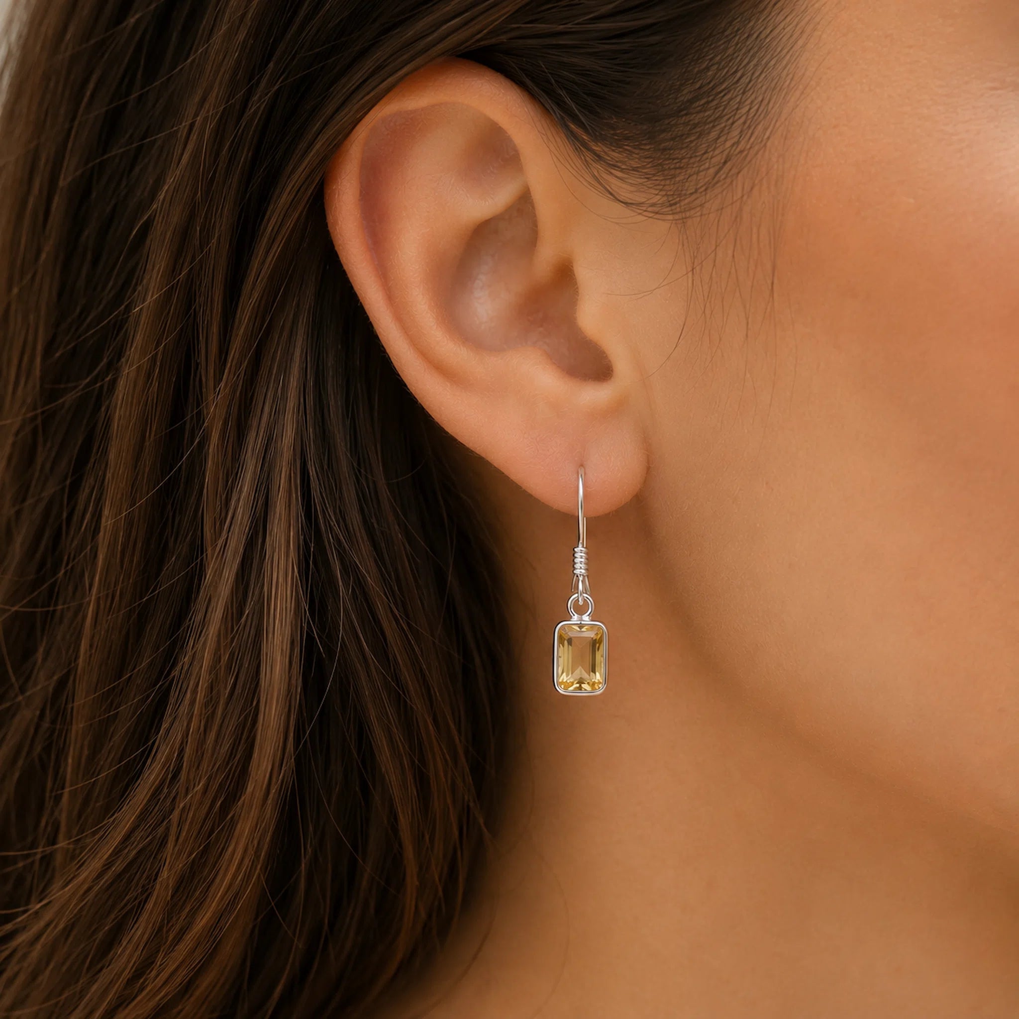 woman wearing a sterling silver french hook earring with a bezel set emerald-cut natural citrine gemstone