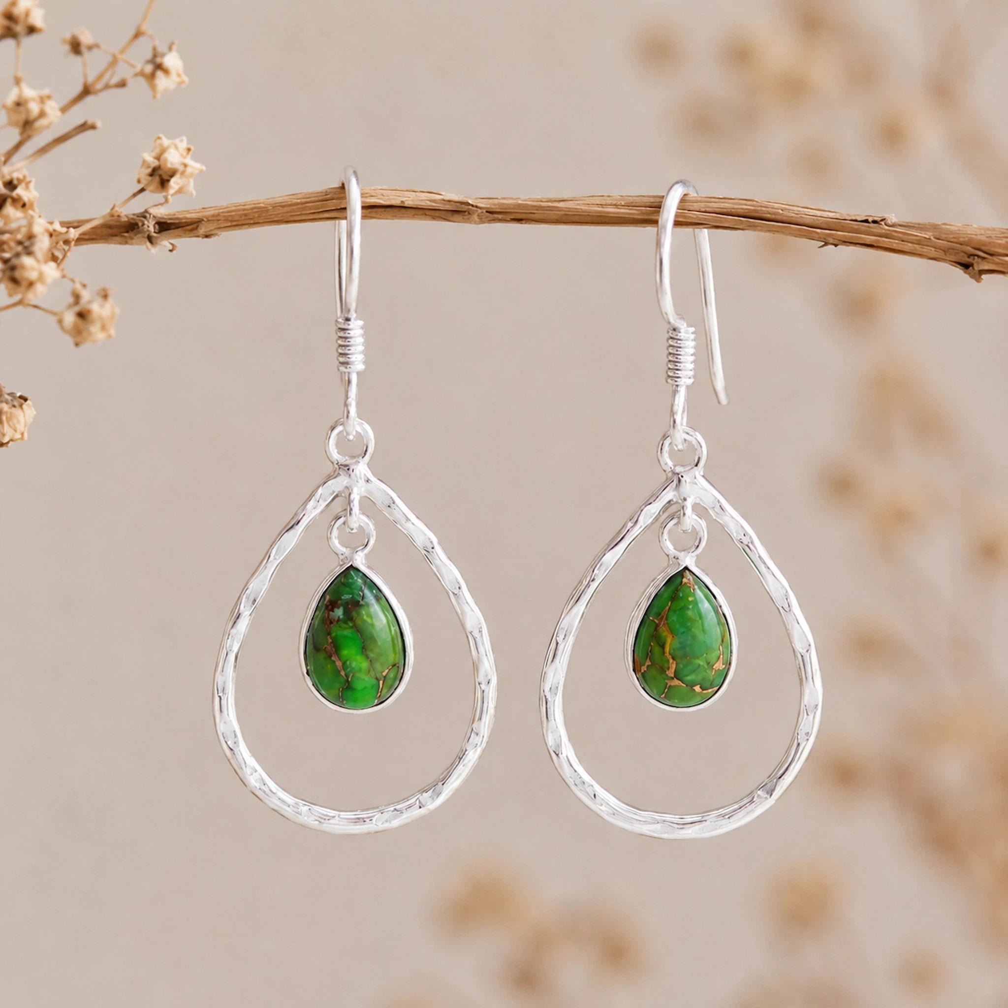 Sterling Silver French Hooks with Teardrop-shaped earrings with green turquoise stones on a branch against a blurred natural background