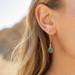 woman wearing a sterling silver long hook earring with a teardrop natural turquoise gemstone