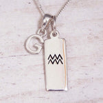 Sterling Silver G Initial and Aquarius Necklace on a fine silver chain against a light wooden background