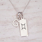 Sterling silver G initial and GeminI Necklace on a fine silver chain on a light wooden background