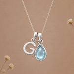 Sterling silver G initial necklace with pale blue March aquamarine in a polished teardrop bezel