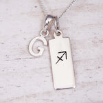 sterling silver necklace with a 'G' initial pendant and a sagittarius zodiac pendant on a light background