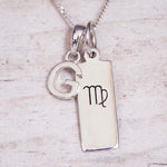 sterling silver initial g virgo zodiac star sign pendant necklace against a light wooden background