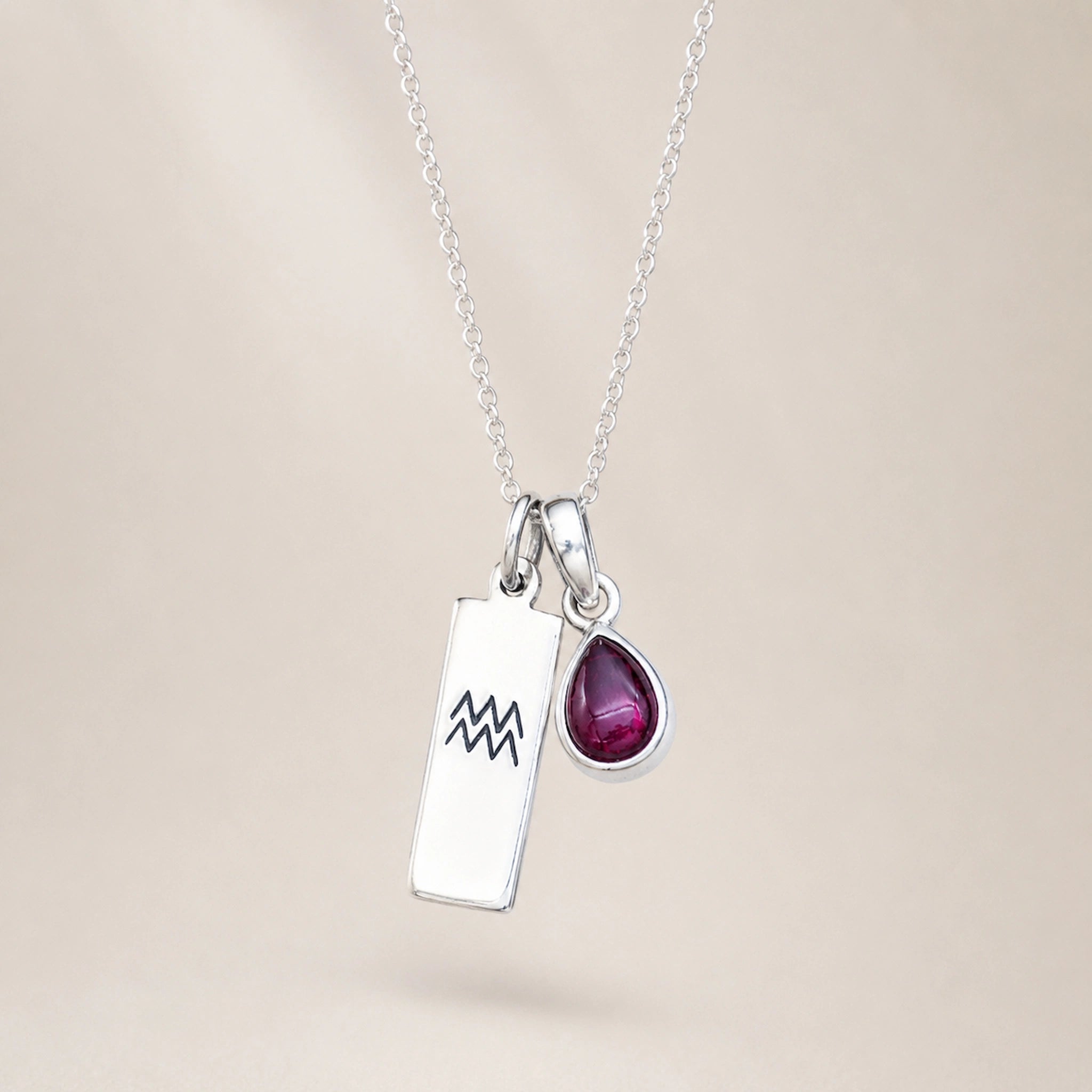 sterling silver double pendant necklace hanging with a rectangle pendant with engraved aquarius line glyph and a teardrop natural garnet january birthstone pendant
