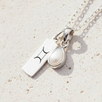 Sterling Silver necklace with a tear drop june birthstone pear pendant with a gemini zodiac pendant on a light background