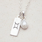Sterling Silver necklace with a tear drop june birthstone pear pendant with a gemini zodiac pendant on a light background