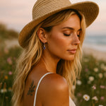 Woman wearing a straw hat in a field of flowers wearing sterling silver amethyst earrings by indie and harper australia