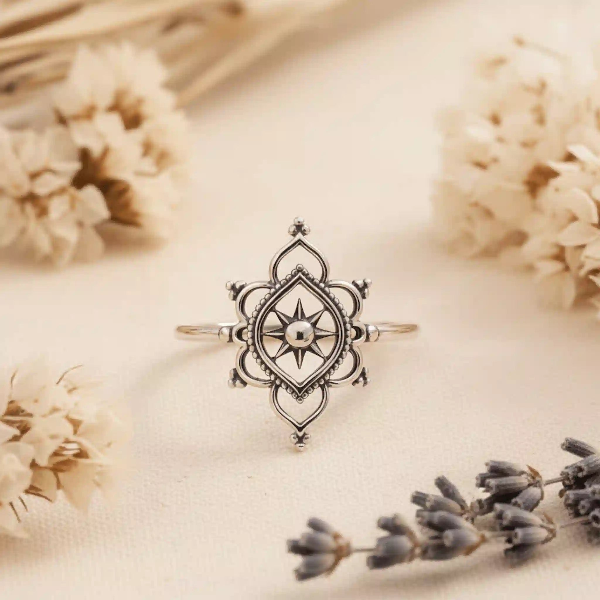 Silver ring with star design on a beige background with flowers