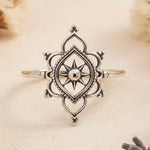 Silver ring with intricate design on a beige fabric background