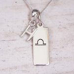 sterling silver initial h libra zodiac star sign pendant necklace against a light wooden background