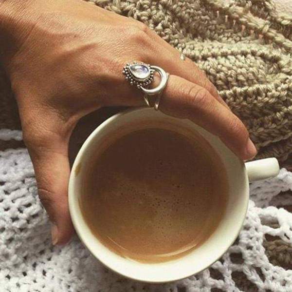 Sterling silver moonstone ring being worn with hand holding a cup of coffee above a woollen blanket - moonstone jewellery australia