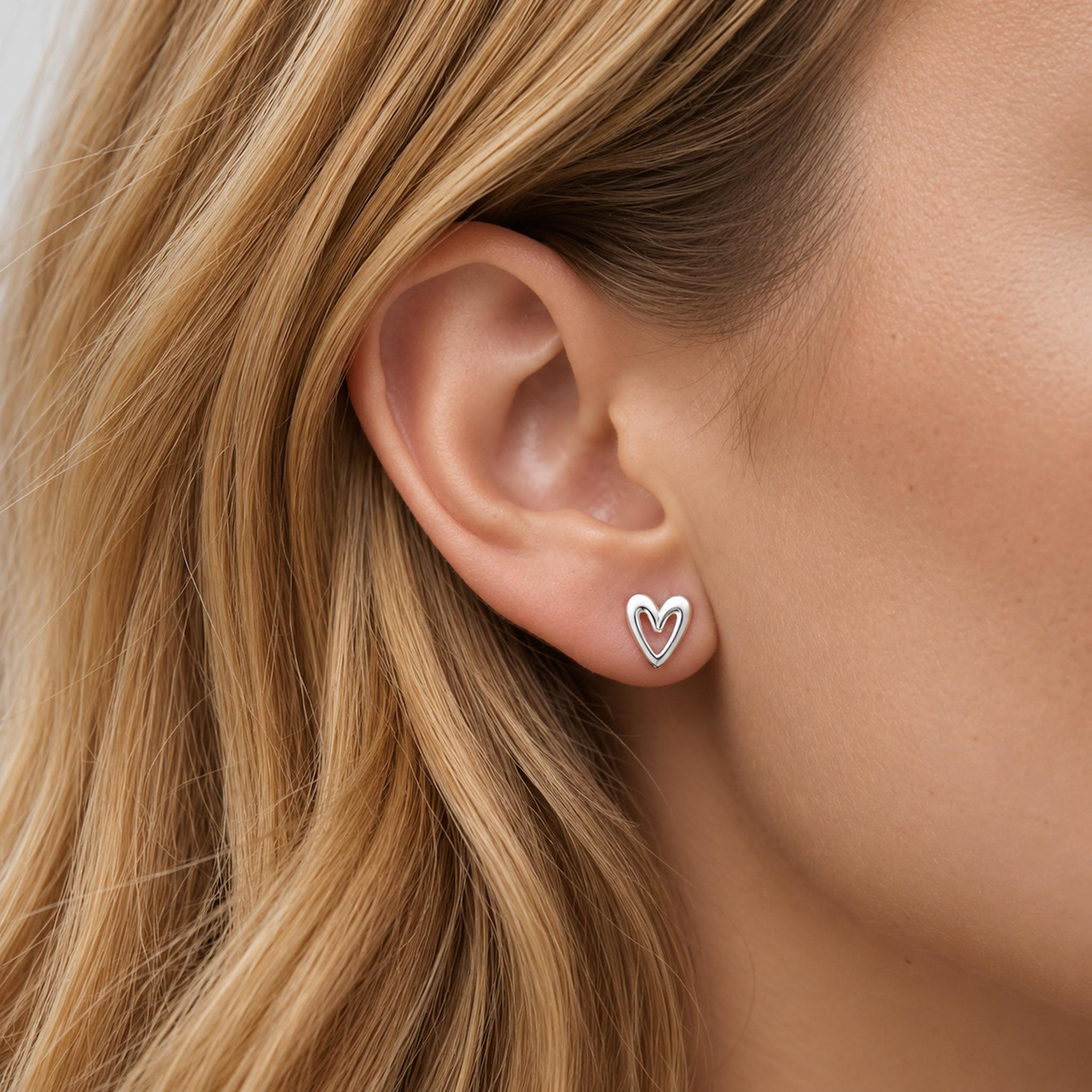 Sterling Silver dainty heart-shaped earrings being worn