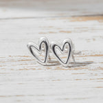 Silver heart-shaped earrings on a light wooden surface