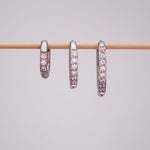 Three stainless steel waterproof pavé silver hoop earrings in three different hoop huggie earring sizes