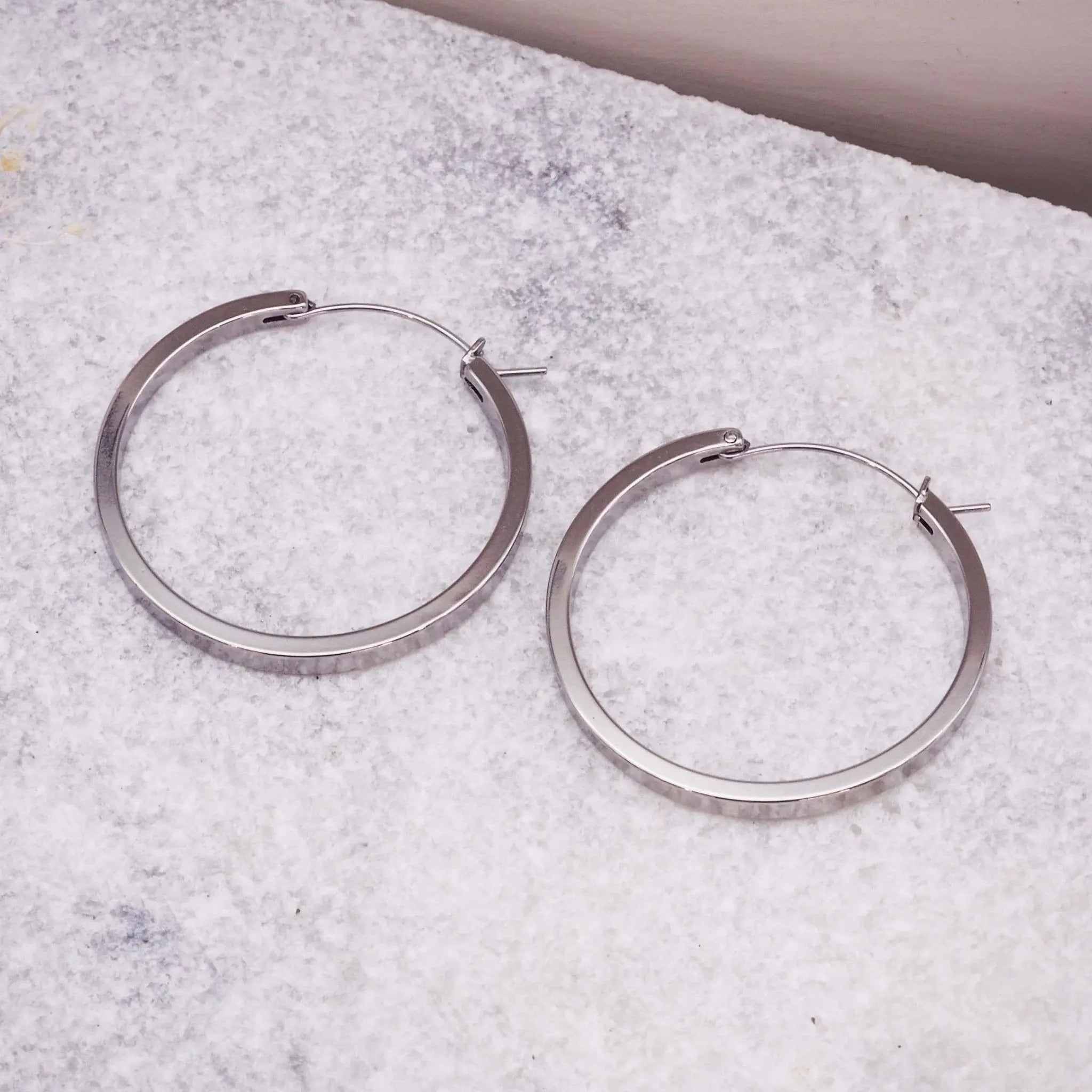 Pair of silver hoop earrings on a textured surface