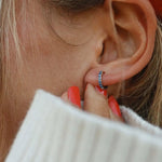 Woman wearing Sterling Silver huggie earrings with blue crystals