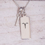 Sterling Silver I Initial pendant and Aries necklace on a fine silver chain on a light wooden background