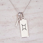 Sterling silver I initial and GeminI Necklace on a fine silver chain on a light wooden background