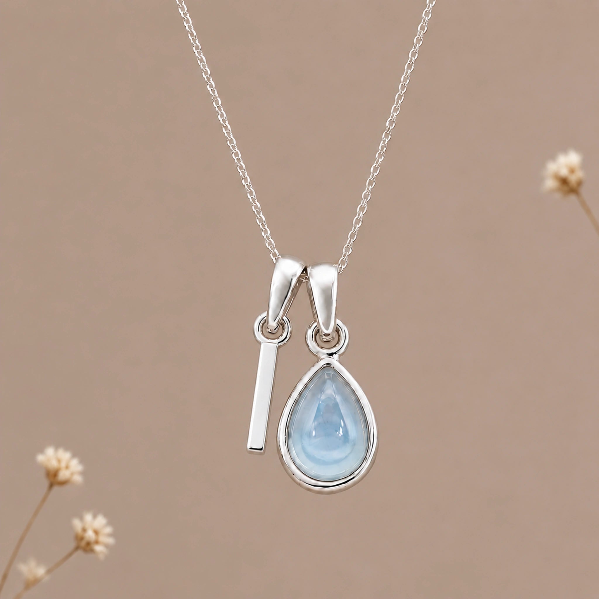 Sterling silver initial I and November natural blue topaz necklace on a taupe background with sparse ivory flowers