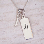 sterling silver initial i leo zodiac star sign pendant necklace against a light wooden background