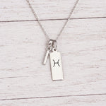  sterling silver I initial Pisces Necklace on a fine silver chain against a light wooden background