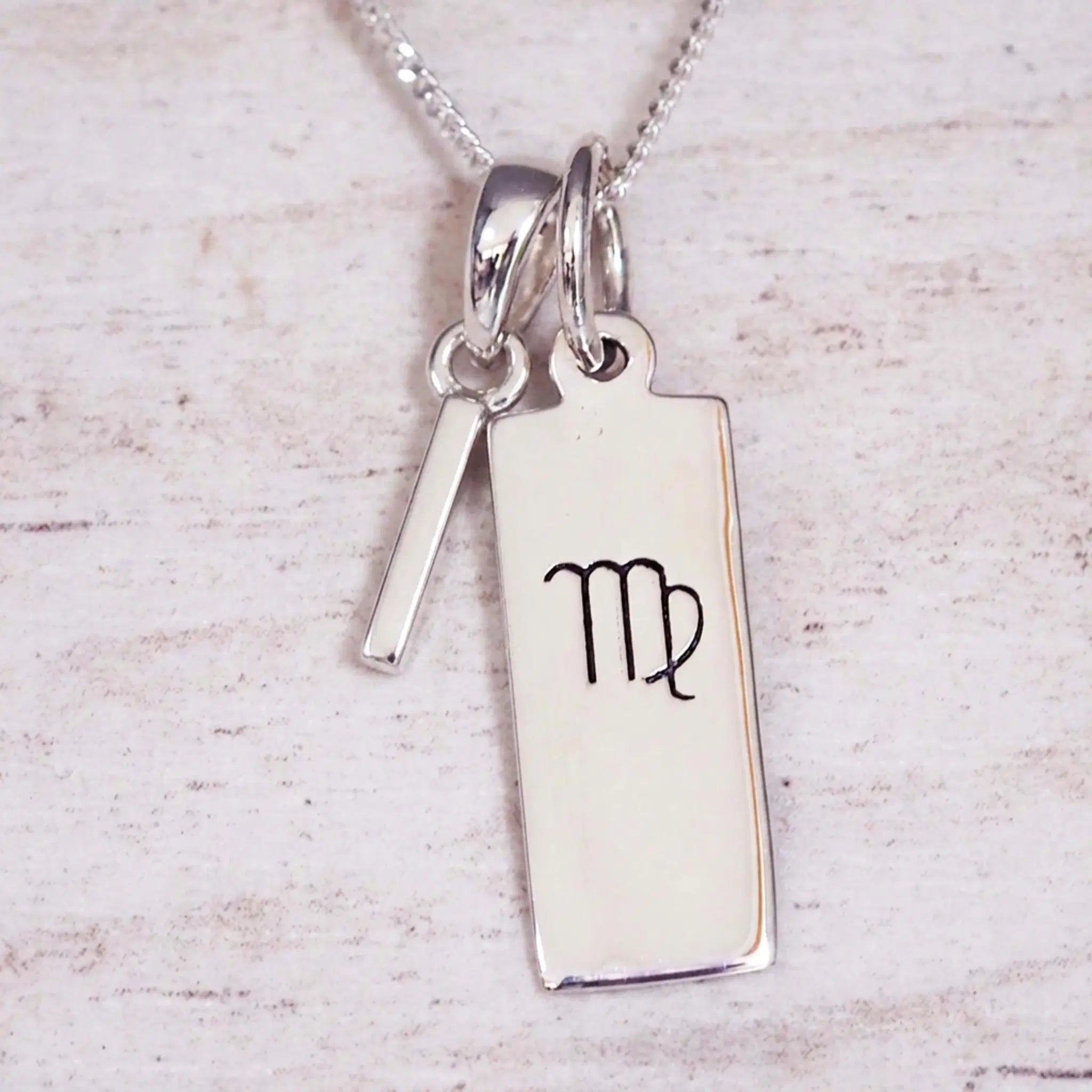sterling silver initial i virgo zodiac star sign pendant necklace against a light wooden background