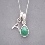 Sterling Silver double pendant necklace with a green teardrop may birthstone emerald pendant and letter 'A' charm on a grey background